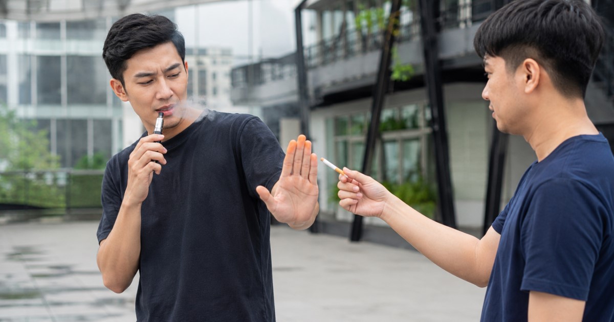 Realistic clinical-public-health scene showing an adult smoker switching from combustible cigarettes to vaping.